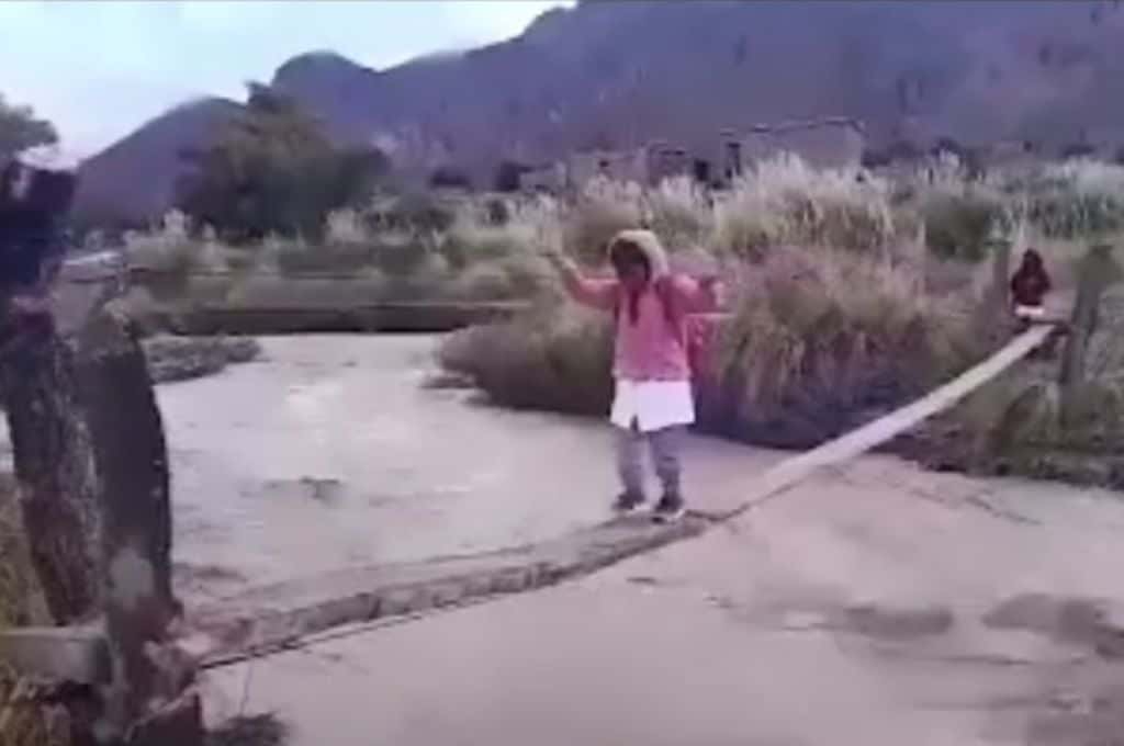 Niños cruzan un peligroso puente